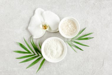 Spa tedavisi konsepti. Doğal organik spa ürünleri, deniz tuzu ve yukarıdaki gri mermer masada tropik palmiye yaprakları. Spa arkaplanı 