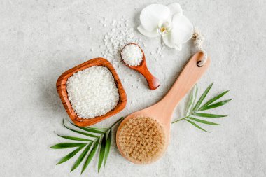 Spa cildi konsepti. Doğal organik spa ürünleri, deniz tuzu, masaj fırçası ve yukarıdaki gri mermer masada tropik palmiye yaprakları.. 
