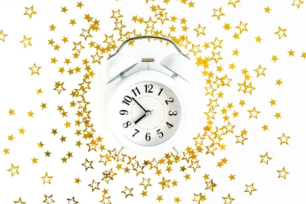 圆圆的镜框，闹钟盖满了金色的星辰，在白色的喜庆的背景上闪闪发光。圣诞节或新年的模式。平躺在床上 — 图库照片