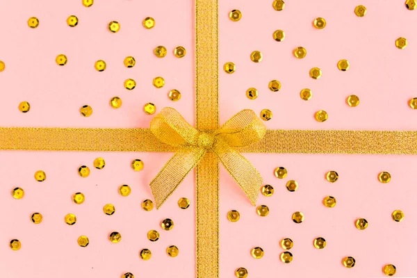 Золота стрічка з бантом, ізольована на рожевому фоні. Барвисте святкування, день народження. Плоский прошарок, вид зверху — стокове фото