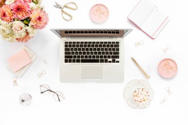 Tarz sahibi kadınların ofis masası. Laptop, bilgisayar, buket ranunculus ve güllerle çalışma alanı, beyaz arka planda pano. Düz yatıyordu. Üst görünüm.