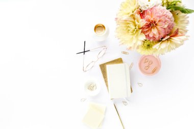 Düz uzanmış kadınların ofis masası. Sarı yıldız çiçekleri, aksesuarlar, altın günlük, beyaz ahşap arka plan. Üst görünüm.