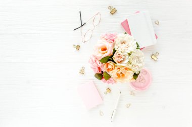 Pembe ve bej güllü kadınların çalışma alanı çiçek buketi, aksesuarlar, günlük, beyaz arka planda gözlük. Düz yerde, üst tarafta. Güzellik günlüğü konsepti.