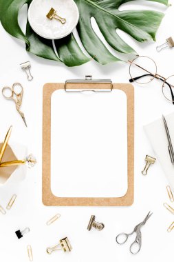 Beyaz arka planda tropikal yaprakları, panosu ve aksesuarları olan ev ofisinin çalışma alanı modeli. Düz yatış, üst görünüm