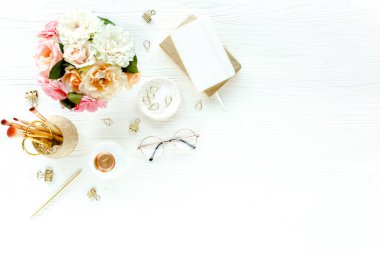 Pembe güller, çiçek buketleri, aksesuarlar, altın günlük, beyaz ahşap arka planda gözlük. Üst görünüm