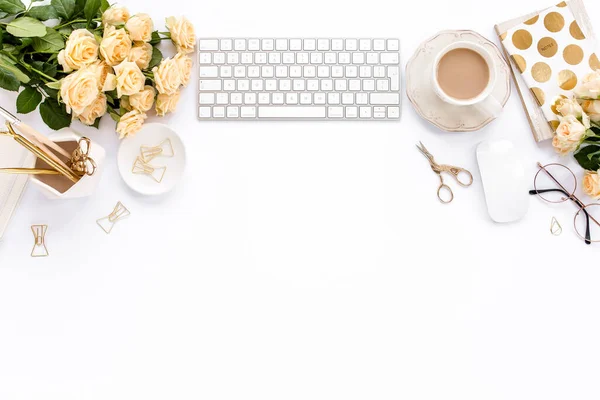 Female workspace with computer, roses flowers, golden accessories, diary, laptop, glasses on white background. Flat lay womens office desk. Top view