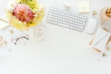 Düz uzanmış kadınların ofis masası. Bilgisayarlı kadın çalışma alanı, pembe ve sarı güller çiçekler, aksesuarlar, günlük, beyaz arka planda gözlük. Üst görünüm