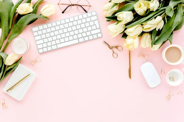 Weiblicher Arbeitsplatz mit Computer, Tulpenblumenstrauß, goldenen Accessoires, Tagebuch, auf rosa Hintergrund. Flach lag der Schreibtisch. Ansicht von oben — Stockfoto