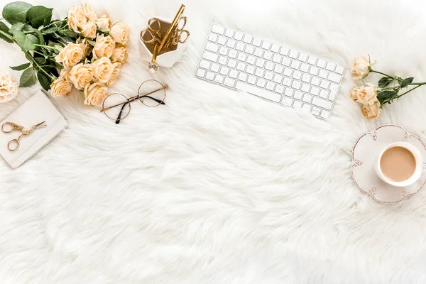 Female workspace with computer, roses flowers, golden accessories, diary, laptop, glasses on white background. Flat lay womens office desk. Top view.