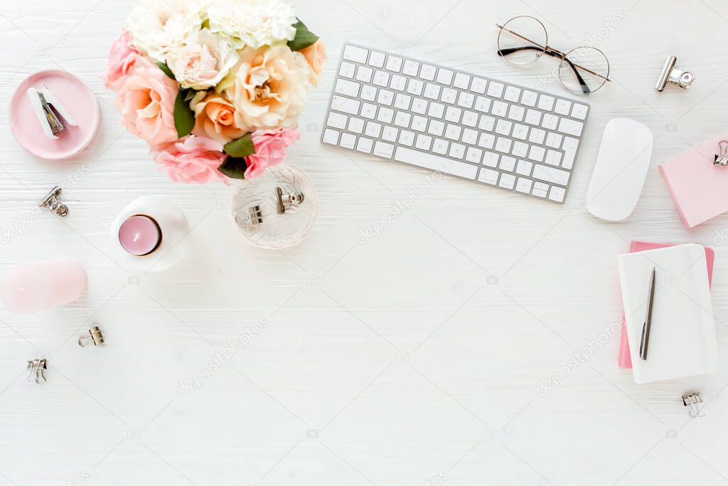 Flat lay womens office desk. Female workspace with computer, pink roses flowers, accessories, golden diary, glasses on white background. Top view 