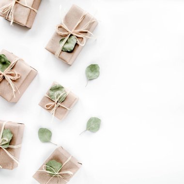 Noel oyuncakları ve el sanatları kutuları. Beyaz arka planda sanat kutuları ve yeşil dallardan oluşan yaratıcı düzenleme çerçevesi. düz yatış, üst görünüm