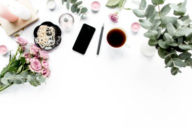 Ofis masası. Çalışma alanı boya fırçası, dizüstü bilgisayar, pembe çiçekler, beyaz arka planda telefon. Düz kompozisyon. Üst görünüm, ev ofis çalışma alanı