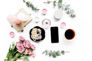 Ofis masası. Çalışma alanı boya fırçası, dizüstü bilgisayar, pembe çiçekler, beyaz arka planda telefon. Düz kompozisyon. Üst görünüm, ev ofis çalışma alanı