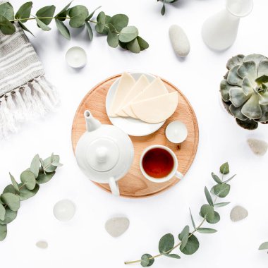 Peynirli kahvaltı, okaliptüs yaprakları, kesme tahtası ve beyaz arka planda siyah çay kompozisyonu. Düz yatış, üst görünüm