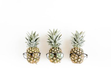 Beyaz arka planda gözlüklü hippi ananasları. Düz yatış, üst görünüm