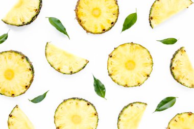 Beyaz arka planda yeşil yapraklı ananas dilimleri. Düz yatış, üst görünüm