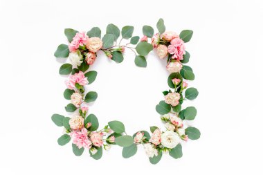 Gül ve karanfilden yapılmış çerçeve, yeşil yapraklar okaliptüs, dallar, beyaz arkaplanda çiçek deseni. Düz yerde, üst tarafta. Sevgililer Günü arkaplanı. 