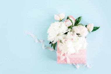Mavi arka planda çiçekler için bir zarf içinde beyaz şakayık demeti. Minimum çiçek konsepti tebrik kartı. Düz yatış, üst görünüm. 