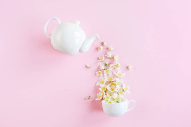 Çaydanlığın yaratıcı düzeni ve pembe arka planda yasemin çiçekleri olan çay fincanı. Yasemin çayı..