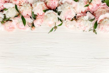 Çiçek çerçeveli çelenk pembe ve bej şakayık çiçekleri çiçek tomurcukları, okaliptüs dalları ve beyaz ahşap arka planda izole edilmiş yapraklar. Düz yatış, üst görünüm