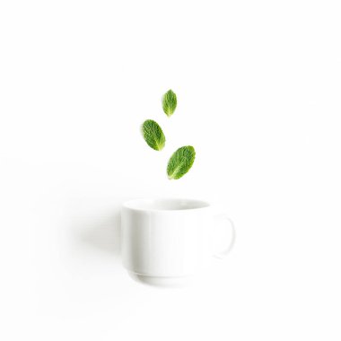 Beyaz arka planda izole edilmiş bir fincan çay ve nane yaprağı. Nane şekeri seti. Darphane deseni. Düz yatıyordu. Üst görünüm.