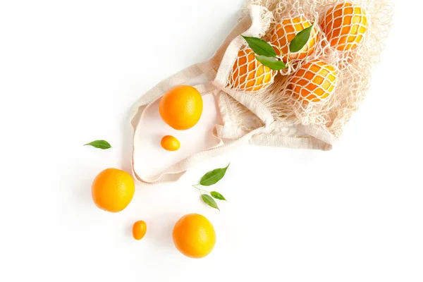 Меш торговый мешок с апельсинами на белом фоне. Шаблон из летних тропических фруктов. Концепция питания. Плоский, вид сверху — стоковое фото