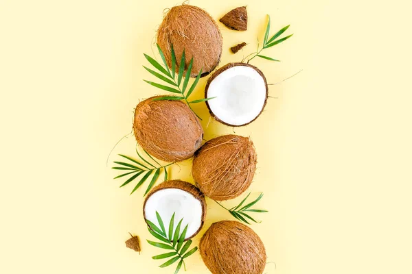 Modello con noci di cocco e foglie di palma tropicale su sfondo giallo. Sfondo tropicale astratto. Posa piatta, vista dall'alto. — Foto Stock