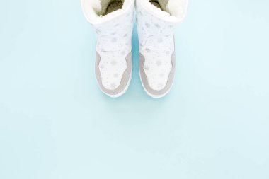 Mavi arka planda izole edilmiş beyaz kadın kış botları. Düz yatış, üst görünüm moda kadınsı arka plan. Güzellik blogu konsepti. Moda blogu görünümü. 