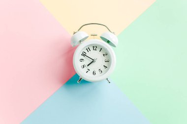 Renkli arka planda beyaz alarmlı saat. Moda minimal tarzı. Güzellik ve moda konsepti. Düz kompozisyon. Üst görünüm.