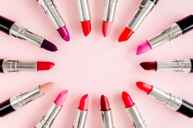 Pembe arka planda renkli ruj seti. Profesyonel dekoratif kozmetik ürünler. Düz kompozisyon güzelliği, moda. düz yatış, üst görünüm
