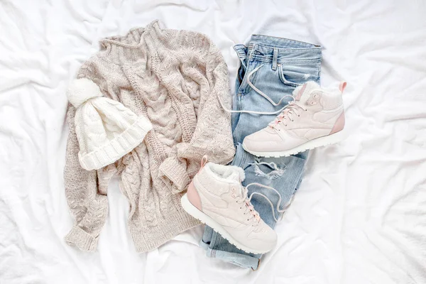 Vêtements et accessoires pour femme sur fond blanc. Pull chaud femme, jeans, baskets. Moderne et tenue. Concept de shopping. Couché plat, vue du dessus. — Photo