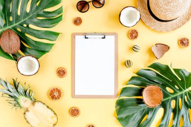Tropikal çerçeve, arka planda pano, egzotik meyveler ve sarı arka planda tropikal palmiye yaprakları. Düz yatış, üst görünüm