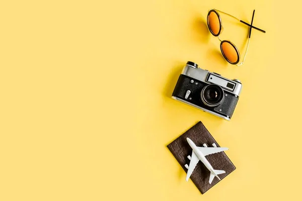 Traveler accessori concetto su sfondo giallo. Fotocamera retrò, modello di aereo, aereo e foglia di palma tropicale. — Foto Stock