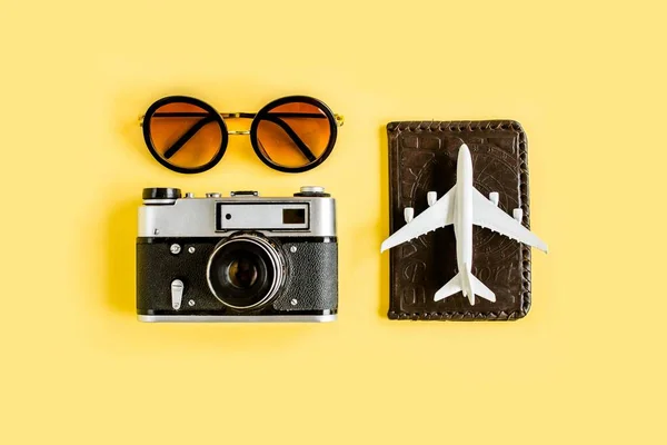 Traveler accessori concetto su sfondo giallo. Fotocamera retrò, modello di aereo, aereo e foglia di palma tropicale. — Foto Stock