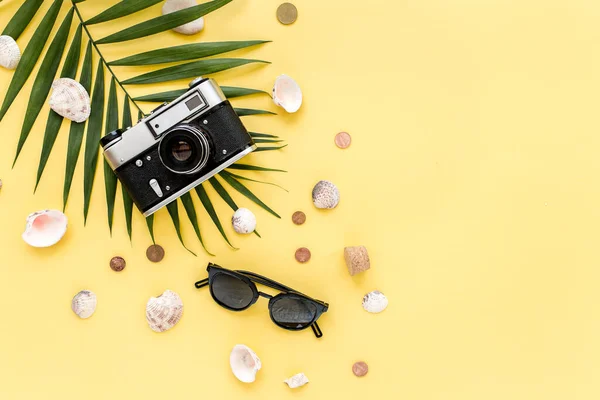 Accessori per viaggiatori su sfondo giallo con foglia di palma, macchina fotografica e occhiali da sole. Posa piatta, vista dall'alto. Sfondo estivo. — Foto Stock