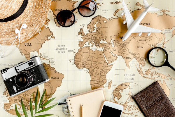 Планирование отпуска, план путешествия, путешествия отпуск с использованием карты мира вместе с другими туристическими принадлежностями. Вид сверху, плоский. 