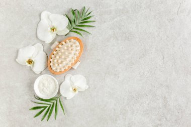 Spa tedavisi konsepti. Doğal kaplıca ürünleri, deniz tuzu, masaj fırçası, yukarıdaki gri mermer masada tropik palmiye yaprakları. Spa arkaplanı
