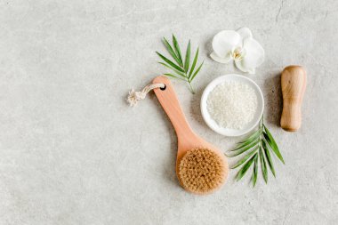 Spa konsepti. Doğal organik spa ürünleri, deniz tuzu, masaj fırçası ve yukarıdaki gri mermer masada tropik palmiye yaprakları. Spa arkaplanı