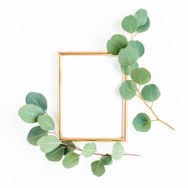 Altın çerçeve yeşil dallar ve beyaz arka planda okaliptüs yapraklarıyla süslenmiştir. Düz uzan, üst görünüm