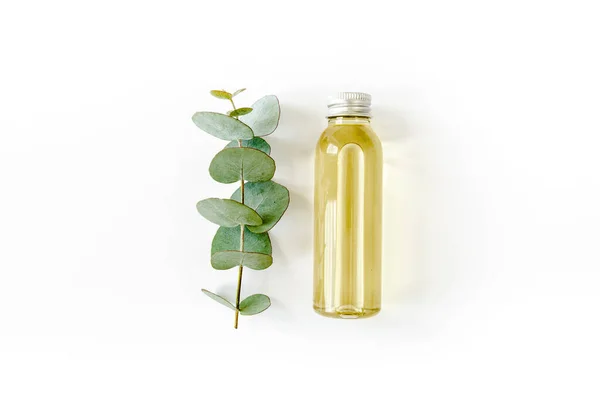 Bottle of eucalyptus essential oil, eucalyptus leaves on white background. Natural, Organic cosmetics products. Flat lay, top view. — Stock Photo, Image