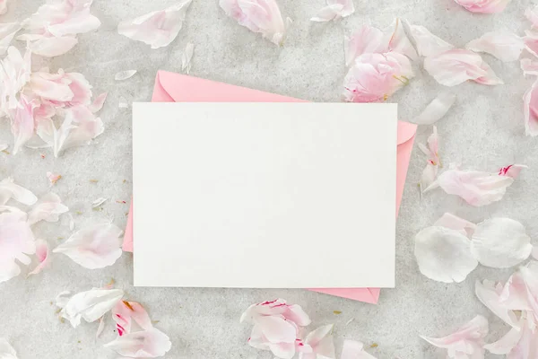 초대, 빈 종이 인사말 카드 회색 테이블 위의 핑크 봉투와 고추. 꽃 배경. 평평하게 누워 있는 위에서 바라본 모습. — 스톡 사진