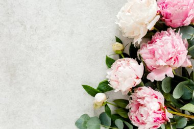 Gri taş masanın üzerinde güzel pembe şakayık çiçekleri ve metin için fotokopi alanı. Düz stil, üst görünüm