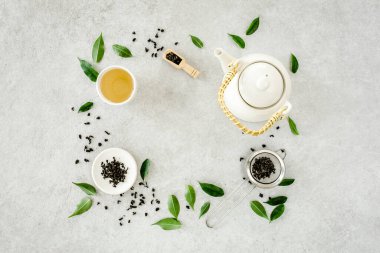 İki beyaz çay fincanı ve yeşil çay yapraklı çaydanlık ile bitki çayı. Düz yerde, üst tarafta. Çay konsepti