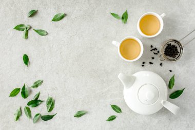 İki beyaz çay fincanı ve yeşil çay yapraklı çaydanlık ile bitki çayı. Düz yerde, üst tarafta. Çay konsepti