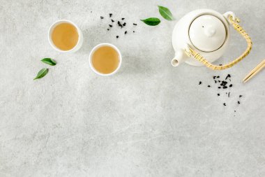 İki beyaz çay fincanı ve yeşil çay yapraklı çaydanlık ile bitki çayı. Düz yerde, üst tarafta. Çay konsepti