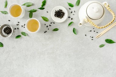 İki beyaz çay fincanı ve yeşil çay yapraklı çaydanlık ile bitki çayı. Düz yerde, üst tarafta. Çay konsepti