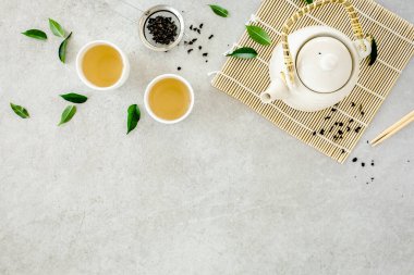 İki beyaz çay fincanı ve yeşil çay yapraklı çaydanlık ile bitki çayı. Düz yerde, üst tarafta. Çay konsepti