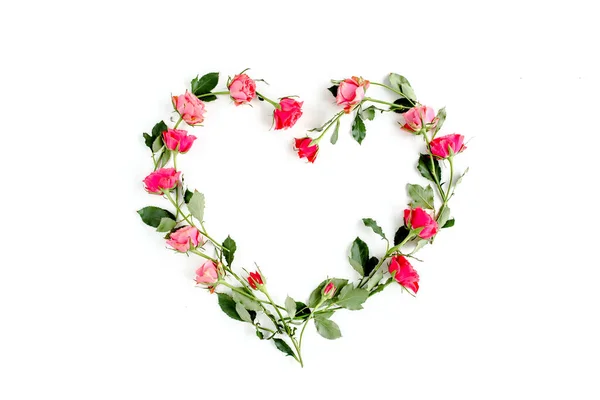 Das Herz ist mit roten Rosen auf weißem Hintergrund gesäumt. Valentins Hintergrund. Florales Muster. Flache Lage, Draufsicht. — Stockfoto