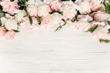 Çiçek çerçeveli çelenk pembe ve bej şakayık çiçekleri çiçek tomurcukları, okaliptüs dalları ve beyaz ahşap arka planda izole edilmiş yapraklar. Düz yatış, üst görünüm