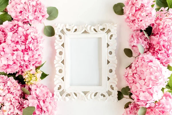Вирізана біла рамка, прикрашена рожевими квітами гортензії на білому тлі. Квіткова концепція. Плоский прошарок, вид зверху . — стокове фото
